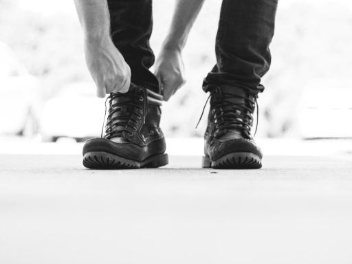 person wearing black leather lace-up boots