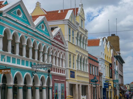 De kleurrijke historische gevels aan de Handelskade in Willemstad, Curaçao, weerspiegeld in het water van de Sint Annabaai