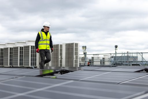 Een elektricien installeert een zonnepaneel op een dak, symbool voor praktische beroepen met toekomst