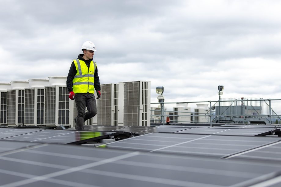 Een elektricien installeert een zonnepaneel op een dak, symbool voor praktische beroepen met toekomst